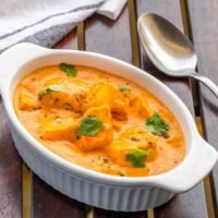 Paneer Butter Masala / butter Paneerf on A Wooden Tables Served in a White Baking Pot. Traditional Indian Paneer /.Cottage Cheese Curry.