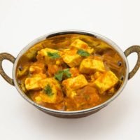 Home made recepie of kadahi paneer or paneer butter masala served in a brass bowl isolated on white available with clipping mask